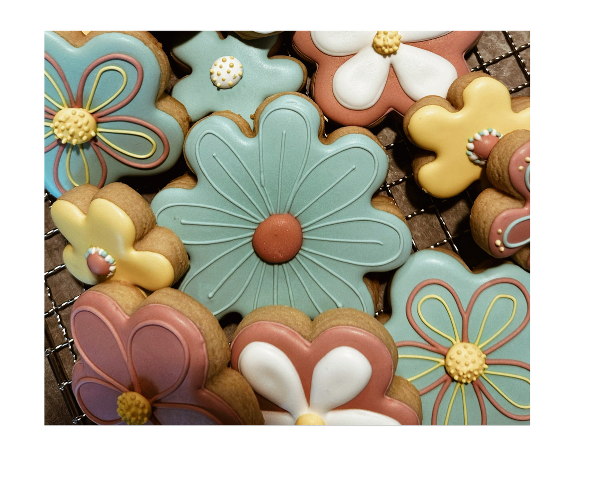 Colorful flower-shaped cookies with intricate icing designs on a cooling rack.
