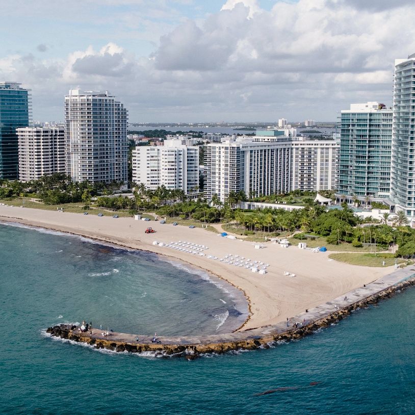 St. Pete beach and skyscrapers are seen from an angle from above, with a cloudy sky.