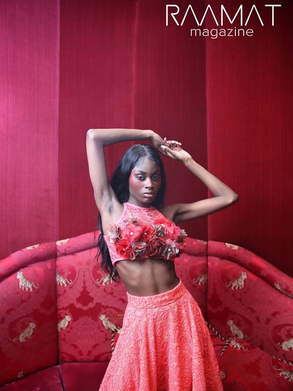 Modèle posant dans une tenue rose sur un canapé rouge.