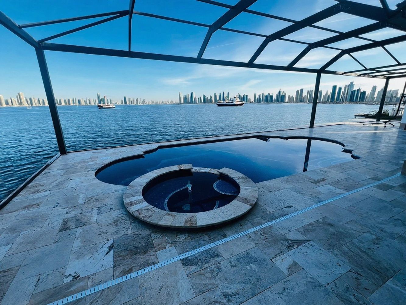 Open-air pool enclosure, overlooking a bay or ocean with a dense skyline in the distance. Gulf Coast
