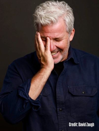 Smiling man with hand on face.
