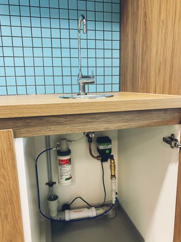 Under-sink water filtration system with modern faucet and blue tiled backsplash.