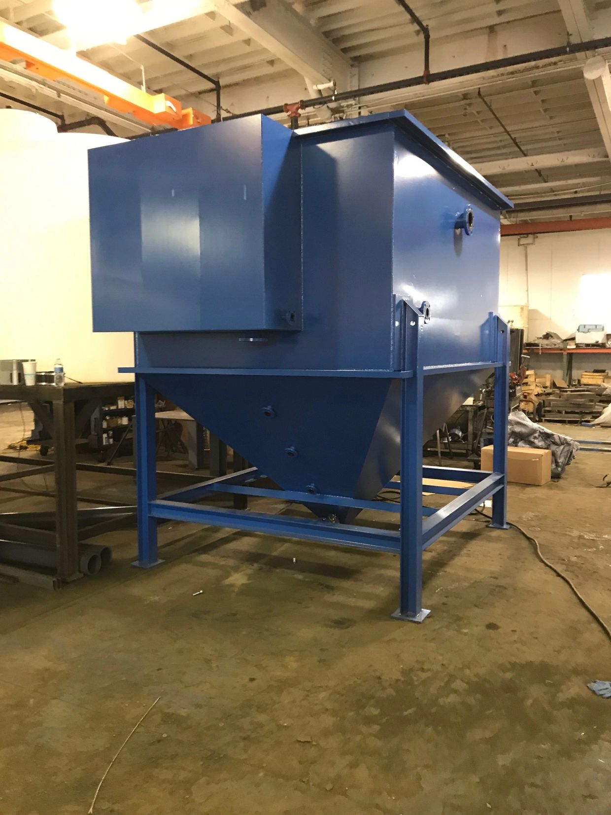 Industrial blue metal hopper in workshop.