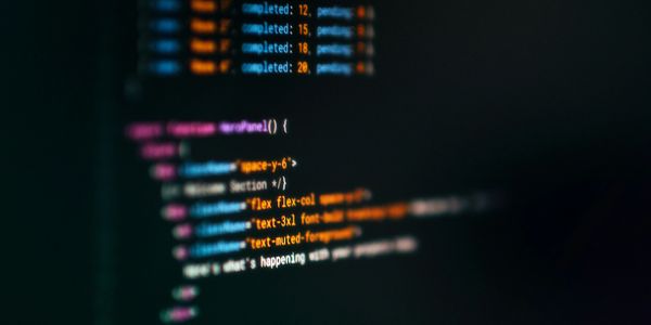 Blurred screen displaying colorful code with function and task completion details.