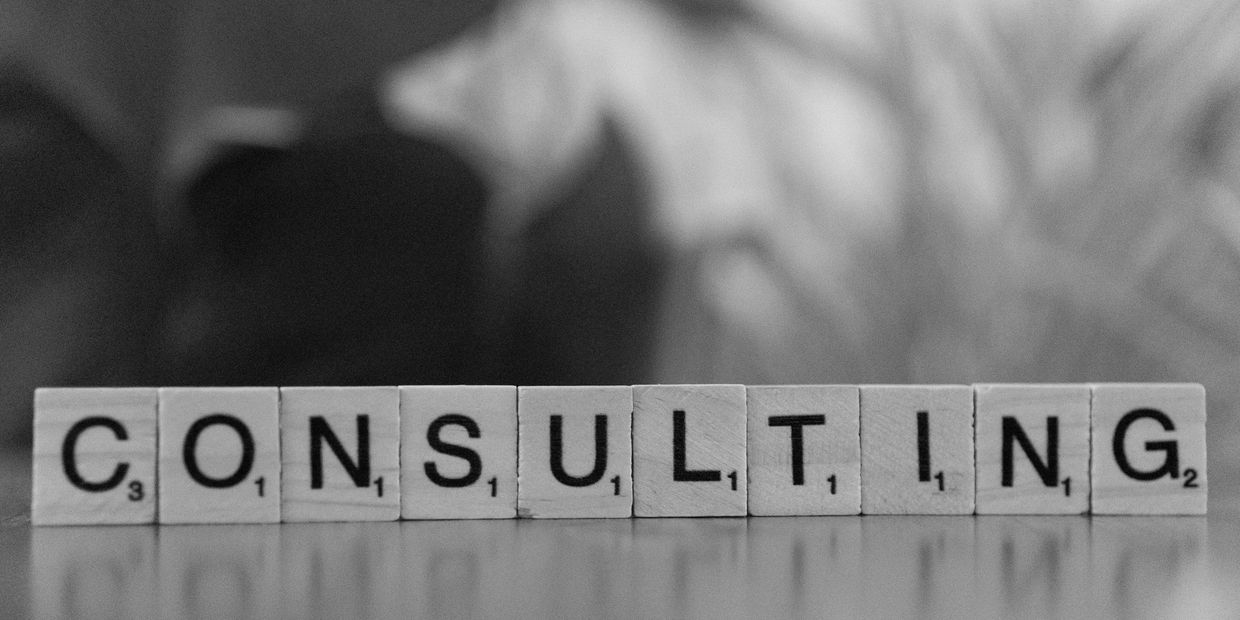 Scrabble tiles spelling the word 'CONSULTING' on a reflective surface.