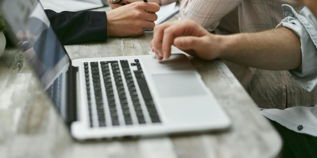 People working together using a laptop and taking notes.