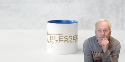 A man in a gray shirt sits thoughtfully beside a white mug with blue interior.