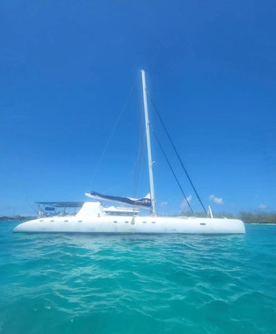 A white catamaran sailing on clear blue waters under a bright sky.