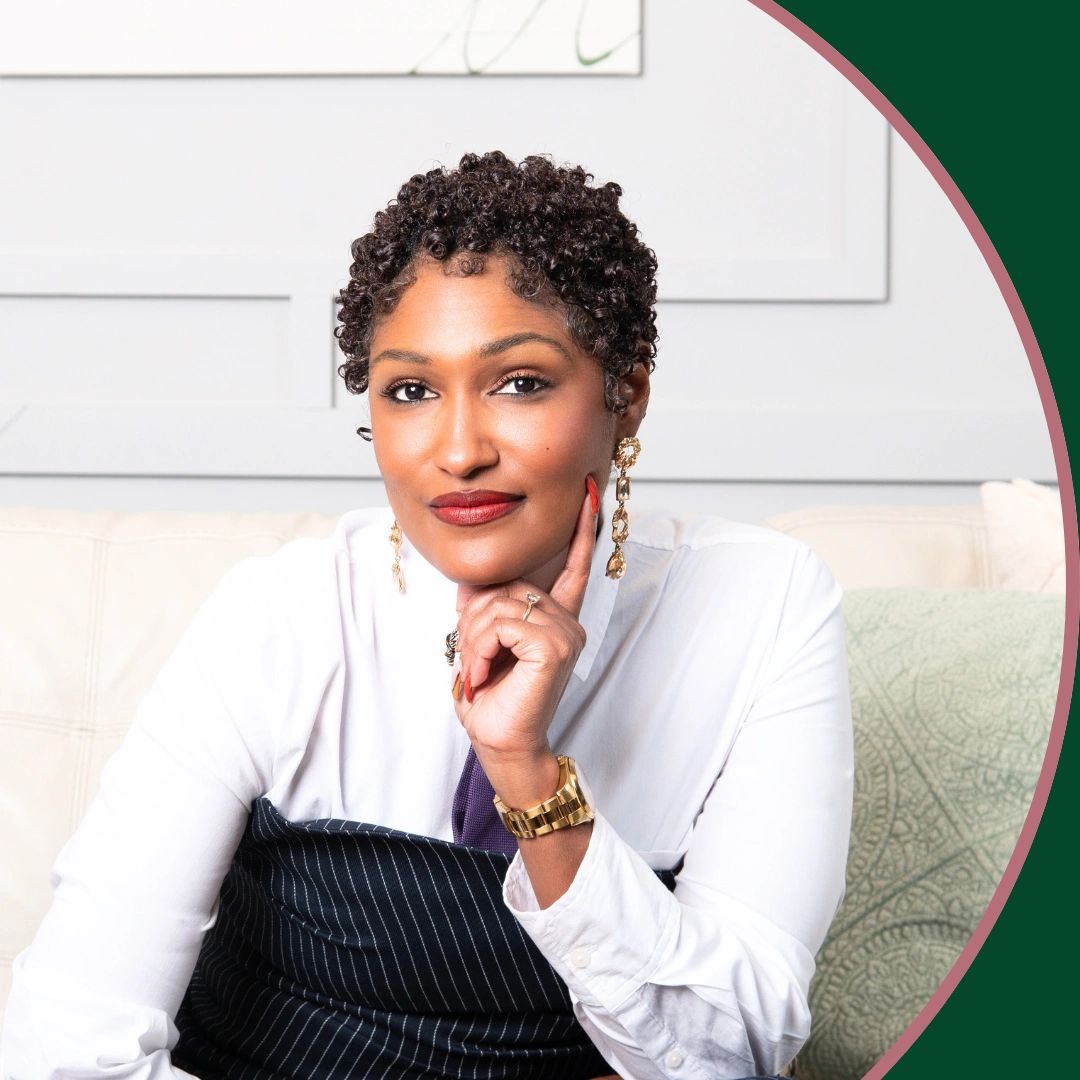 Confident woman with curly hair and gold jewelry, sitting thoughtfully.