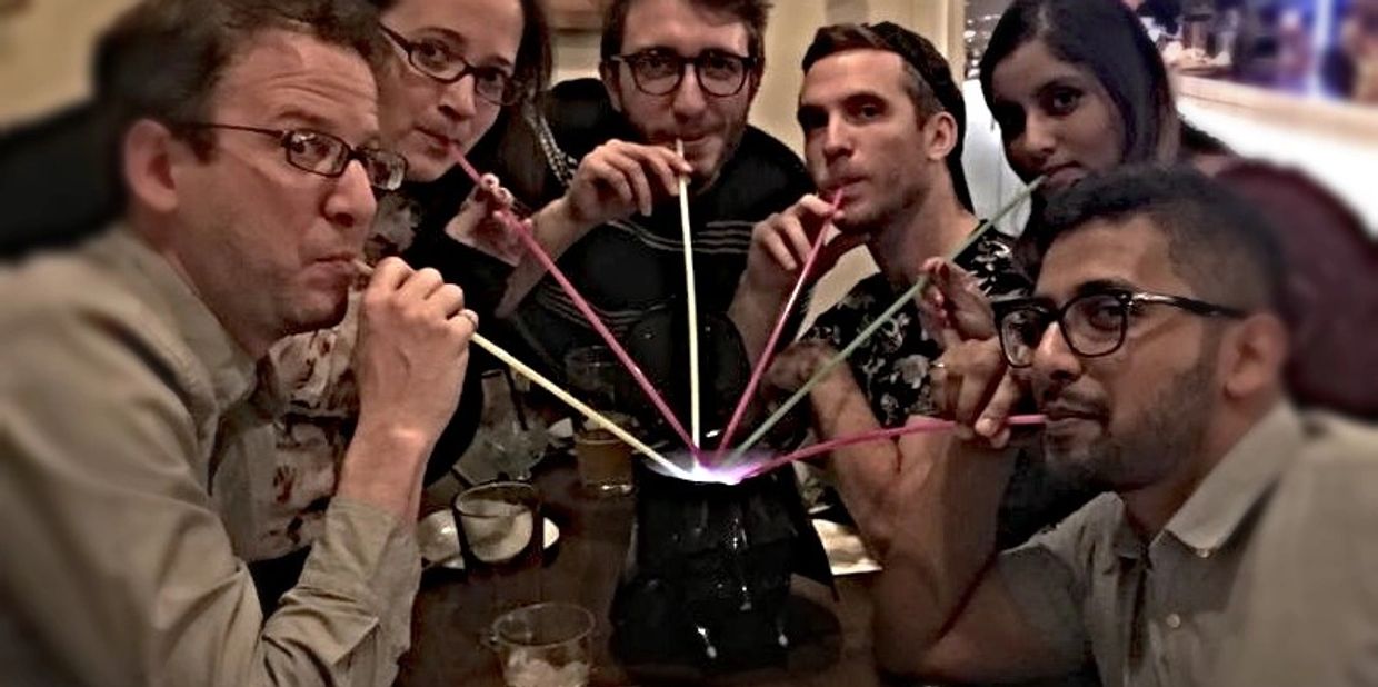 Group of people adults with long colourful straws from a communal drink