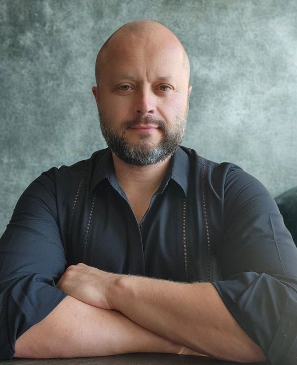 Bald man with beard and crossed arms.
