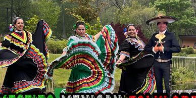 Dancers in traditional colorful Mexican attire performing outdoors.