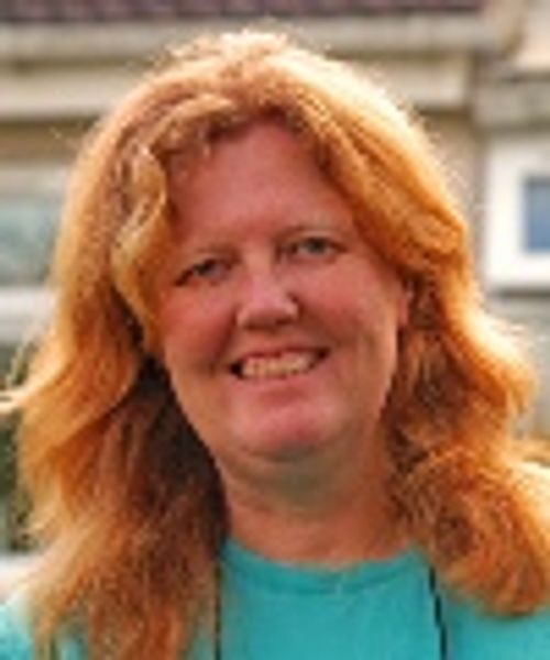 Smiling woman with red hair outdoors.