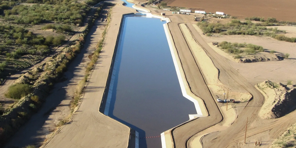 A long, narrow water canal surrounded by desert and farmland.