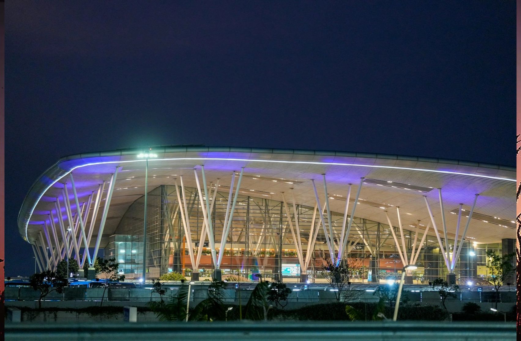 Modern airport terminal illuminated at night with sleek architecture.