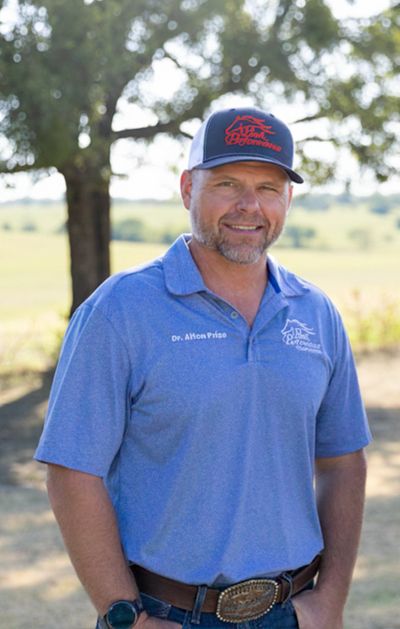 Man in blue shirt and cap outdoors, smiling.