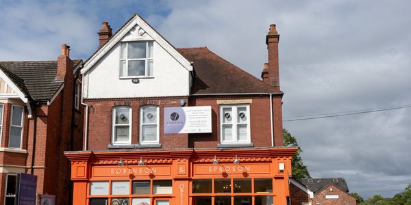 Bright orange facade of Robinson & Sproson optician on a sunny day.