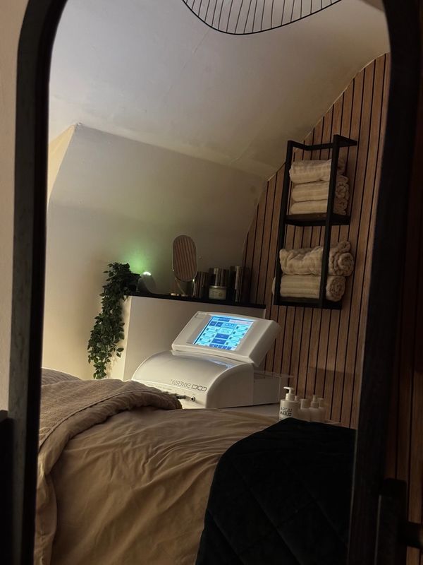 Cozy spa room with a treatment bed and skincare equipment.