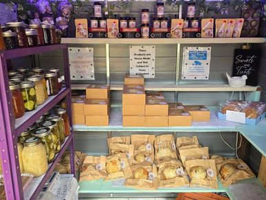 Display of homemade canned goods and baked treats on shelves.