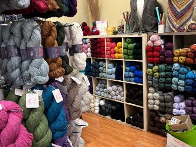 Colorful yarn skeins organized on shelves and racks in a craft room.