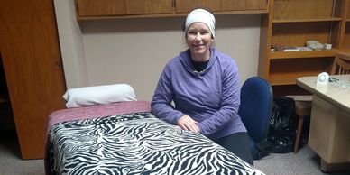 Woman sitting beside a zebra-striped bed in a room.