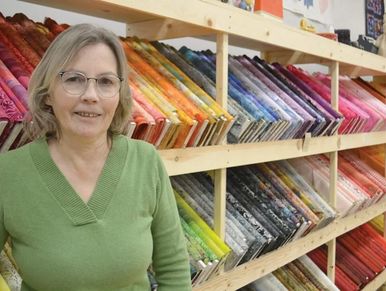 Woman in green sweater with colorful fabric rolls