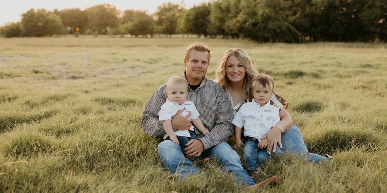 A family of four sitting on grass during sunset.