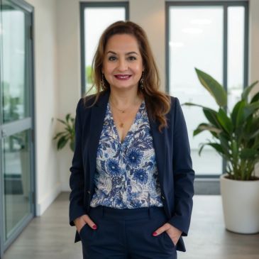 Professional woman in a navy suit standing in an office corridor.