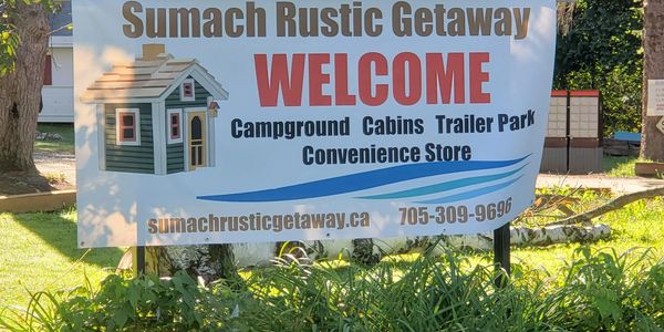Welcome sign for Sumach Rustic Getaway with campground and cabin facilities.