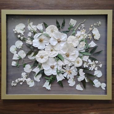 Framed art of white flowers and green leaves.