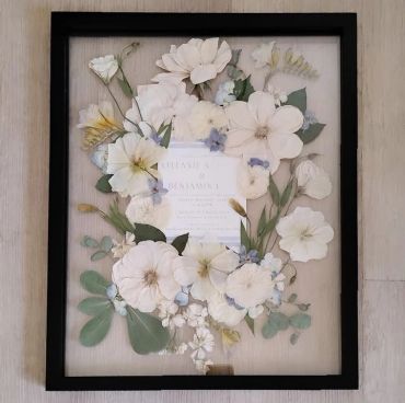 Framed arrangement of delicate white paper flowers.