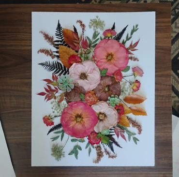 Pressed floral arrangement with vibrant flowers and leaves.
