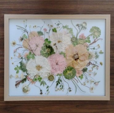 Pressed flowers framed art with pink, white, and green accents.