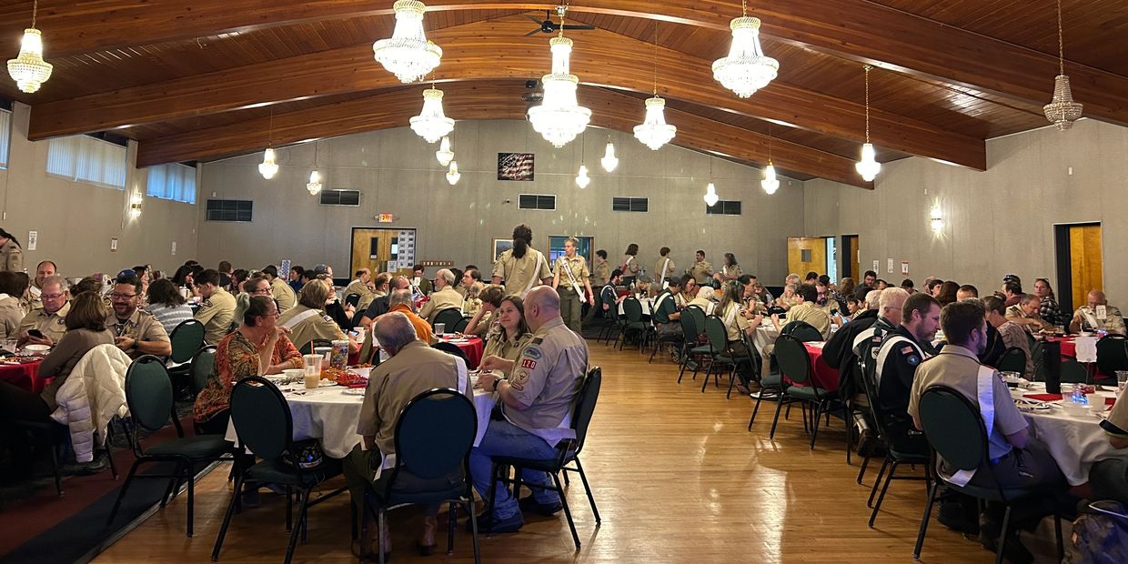 Large indoor gathering of people seated at round tables.
