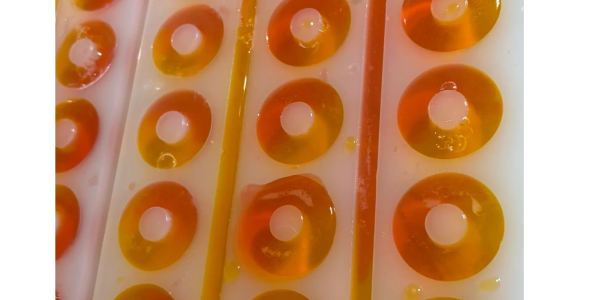 Orange gummy rings in a mold.