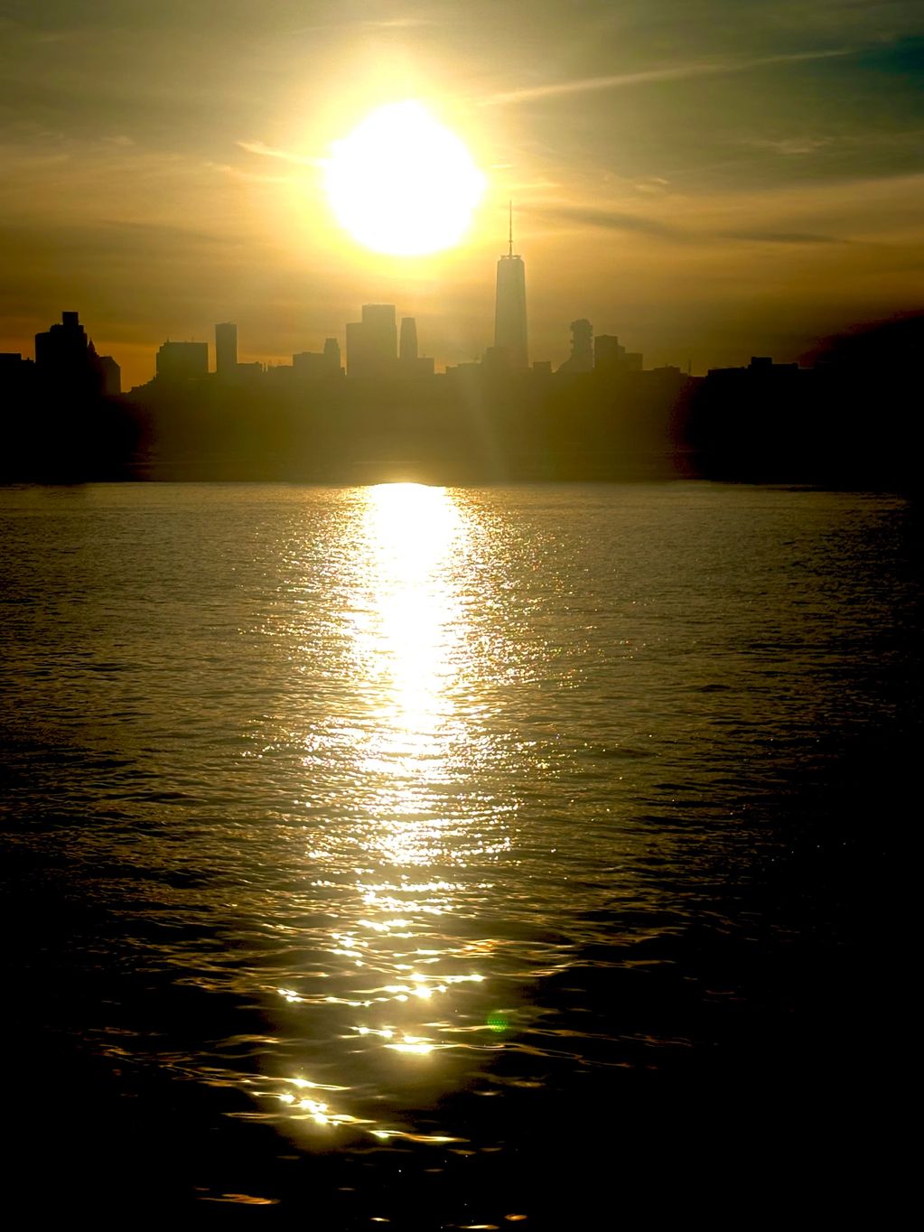 Sunset over a city skyline with water reflecting golden light.