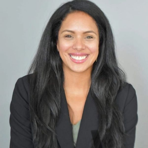 Smiling woman with long black hair in a black blazer.