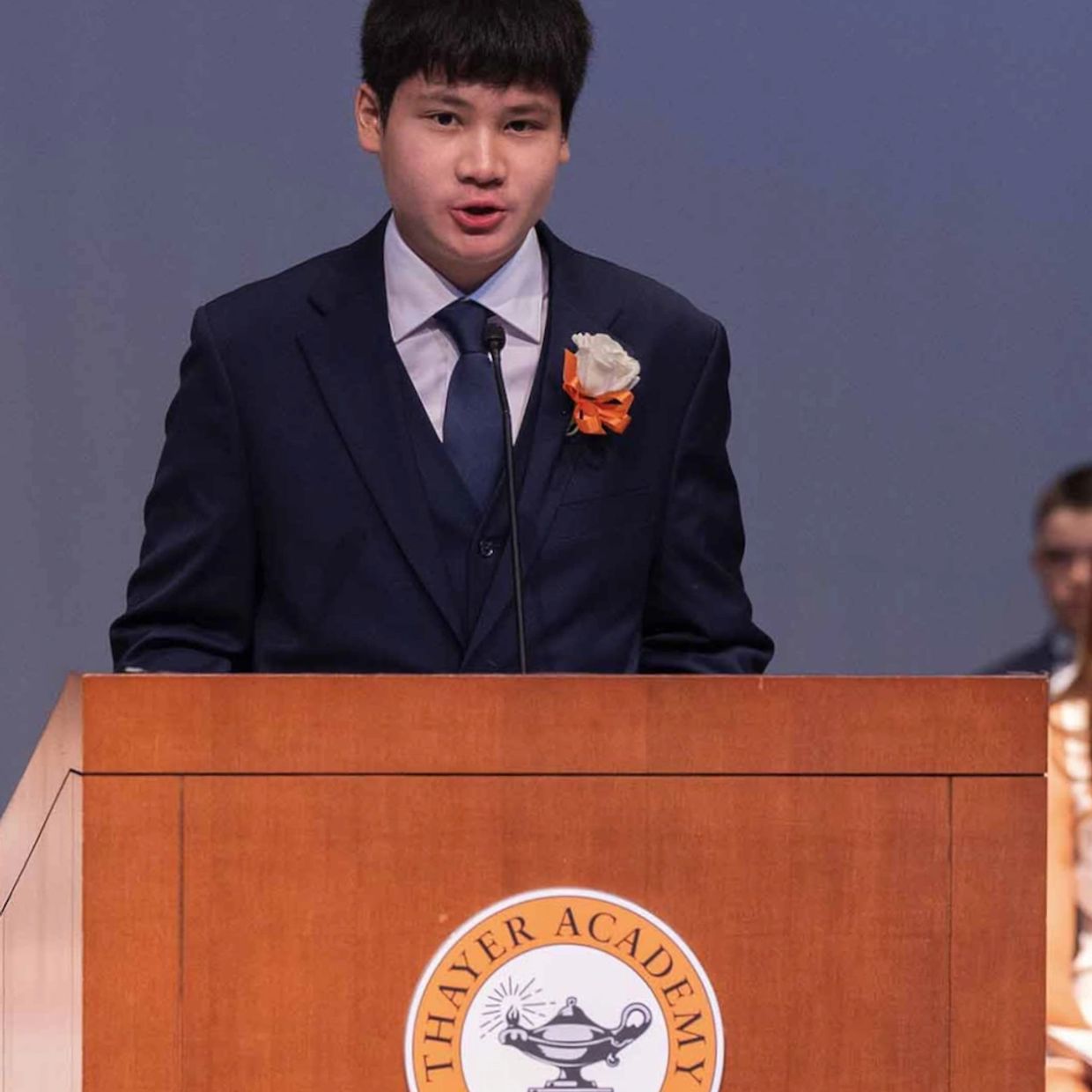 Student in a suit speaking at Thayer Academy podium.