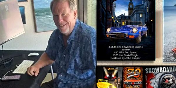 Man sitting at a desk with a computer and car posters on the wall.