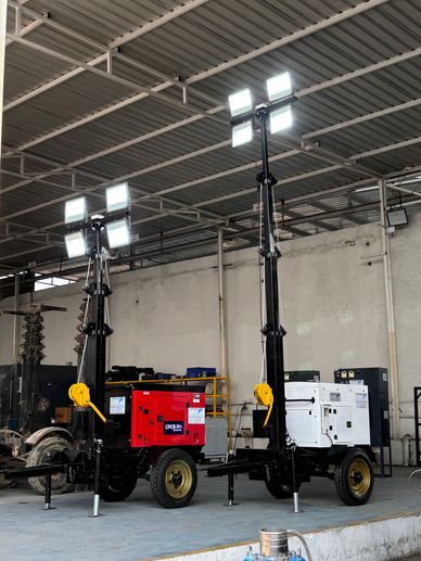 Two portable light towers with bright lights in an indoor industrial setting.