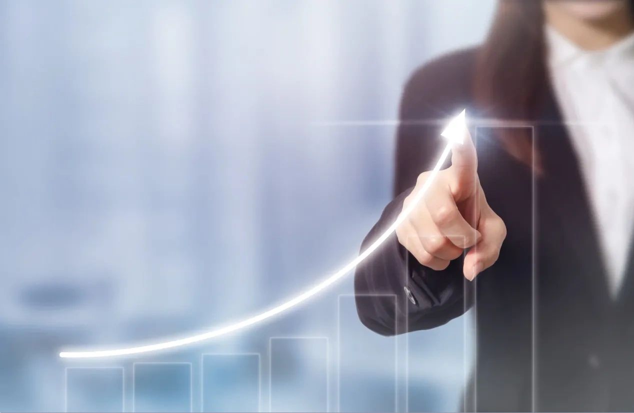 Woman in a suit shows growth trajectory on a graph.