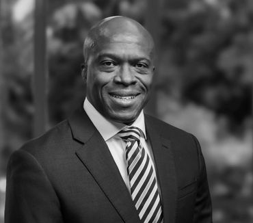Smiling man in suit and striped tie, black and white portrait.