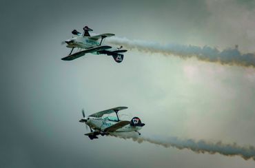 Two stunt planes flying in formation, emitting smoke trails.