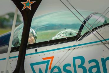 Pilot seated inside a small aircraft cockpit, smiling.