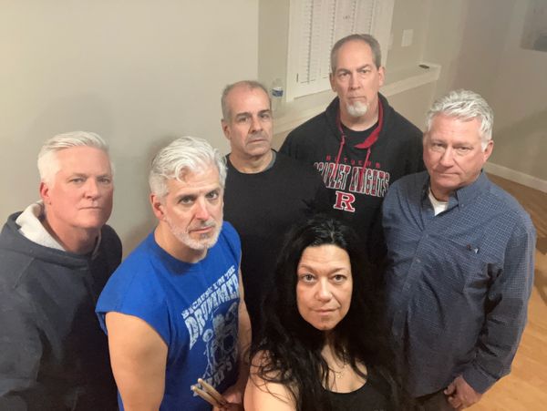 Group of six adults posing indoors, looking at the camera.