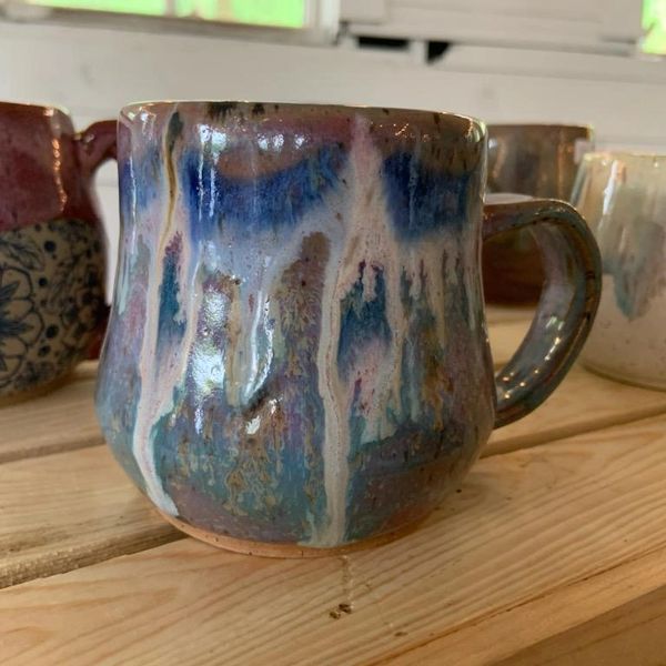 Handcrafted ceramic mug with blue and white glaze on a wooden surface.