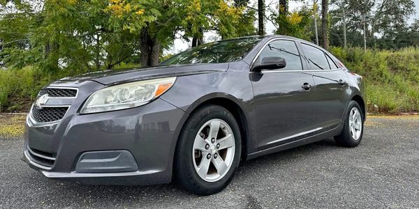 Gray Chevrolet sedan parked outdoors with trees in the background.