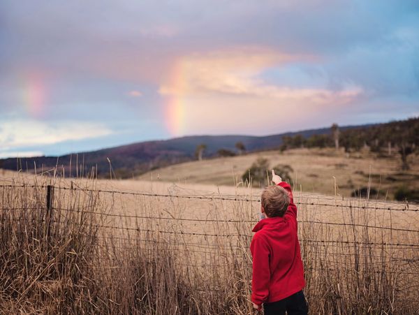 A child staring at the rainbow in the sky