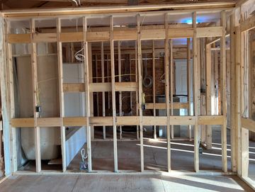 Interior view of a house under construction with exposed wooden framing.
