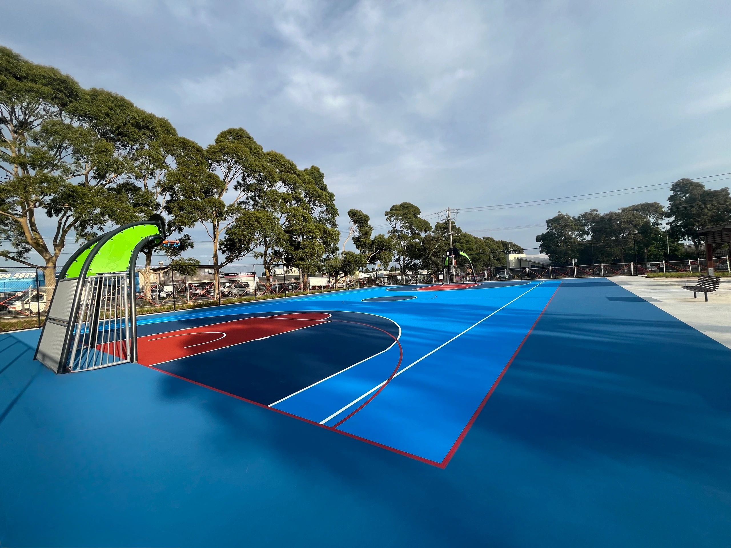 A vibrant blue and red basketball court under a clear sky.